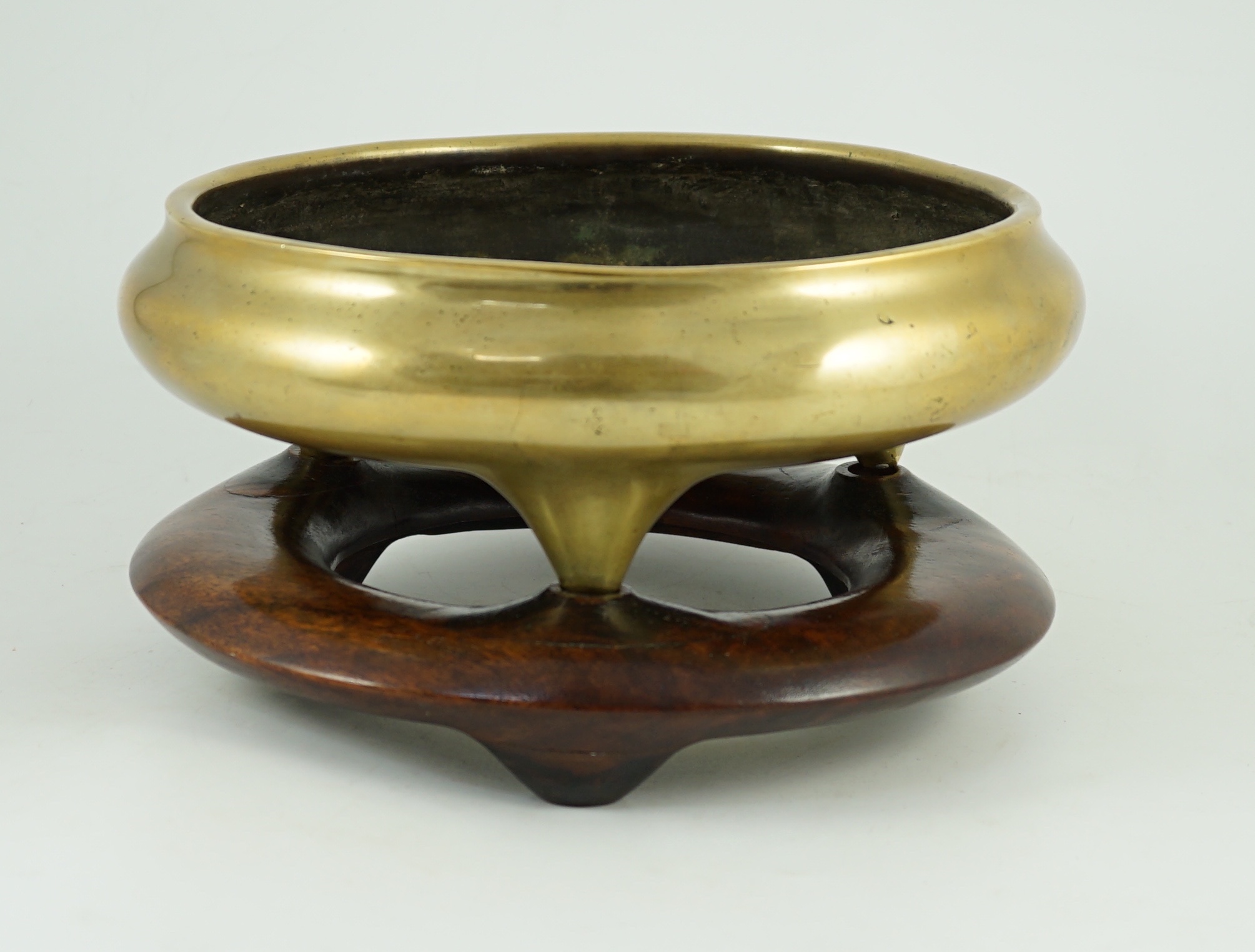 A large Chinese polished bronze tripod censer, 19th century, private four character seal mark, 29.5 cm diameter, Disc shaped rosewood stand